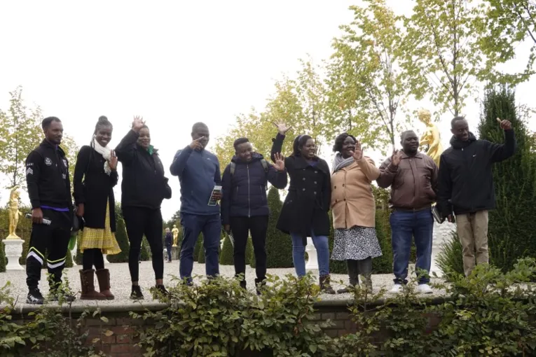 Eine Gruppe Personen steht winkend auf einer Gartenb&uuml;hne