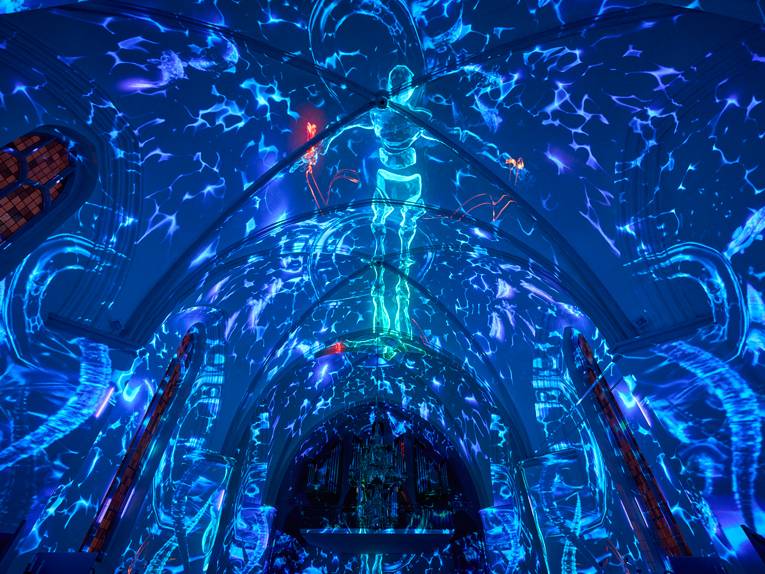 Ein Kirchengewölbe wird mit Wassermotiven einer Lichtprojektion beleuchtet