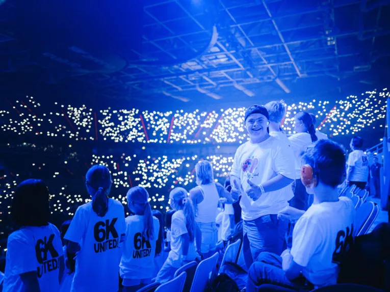 Tausende Kinder singen in einem blau erleuchteten Stadion