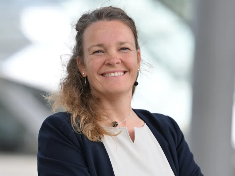 Eine Frau schaut in die Kamera und lacht.