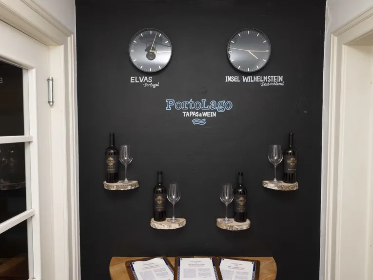 Dunkle Wand, zwei Uhren, die die Uhrzeit in Portugal und Deutschland anzeigen, Weine und Men&uuml;karte