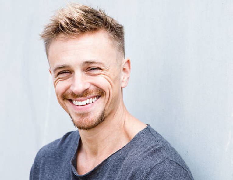 Porträt eines lachenden jungen Mannes mit kurzem Haar und Bart