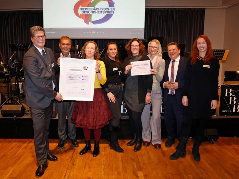 Menschengruppe posiert mit Urkunden für die Kamera, im Hintergrund steht "Niedersächsischer Gesundheitspreis"