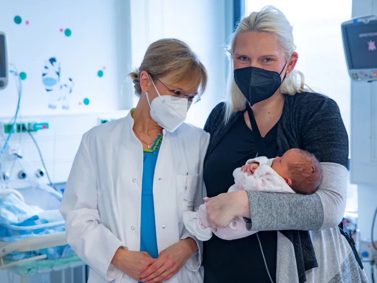 Zwei Frauen, eine hält einen Säugling auf dem Arm