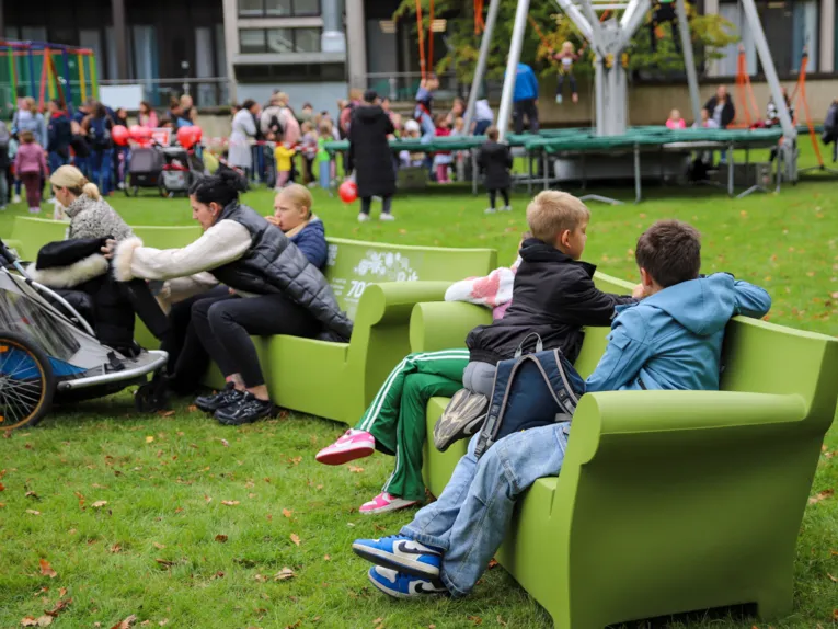 Kinder und Erwachsene auf gr&uuml;nen Sofas im Tiergarten.