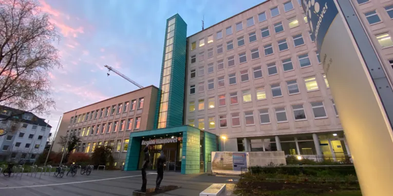Gebäude der Region Hannover, Hildesheimer Str. 20. Im Hintergrund ist ein Baukran zu sehen. Der Eingang und ein angebauter Fahrstuhl sind in der Farbe türkis angelaufenen Kupfers.