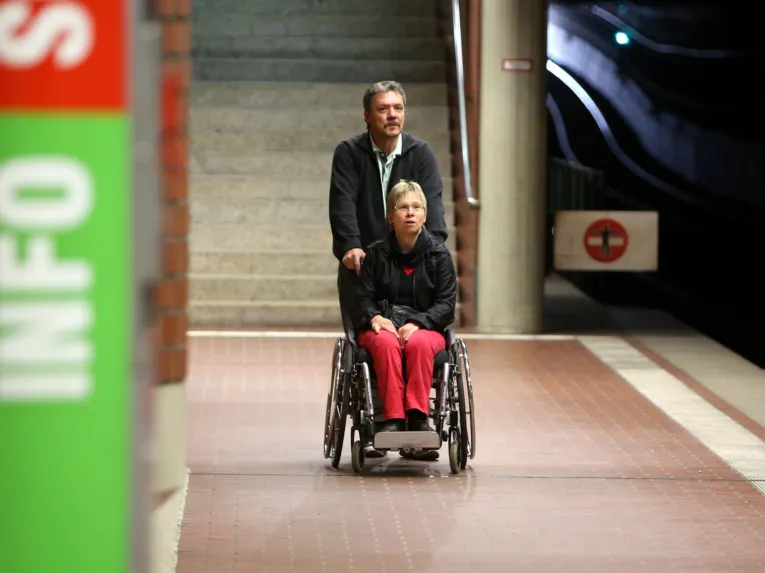Der Fahrgastbegleiter begleitet die Rollstuhlfahrerin auf ihrer Fahrt mit der Stadtbahn.