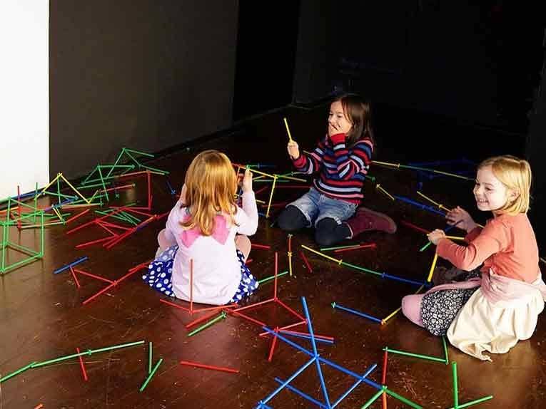 Drei kleine Mädchen bauen und spielen gemeinsam mit bunten Stäbchen
