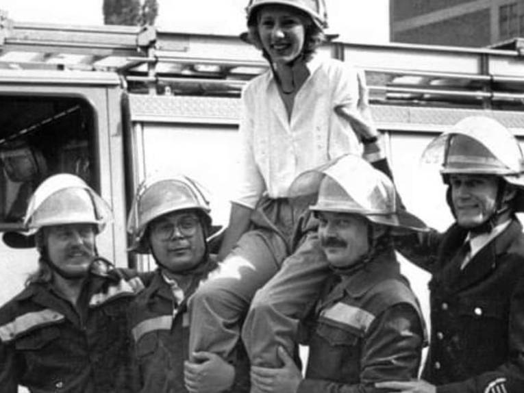 Eine Frau wird von mehreren Feuerwehrmännern auf den Schultern getragen.