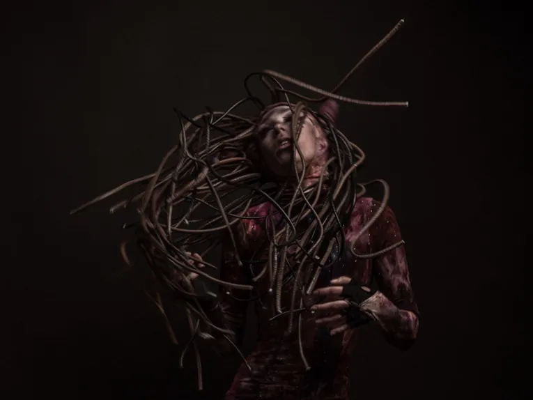 Dramatische Porträtaufnahme einer Person mit wirbelndem Kabel-Haarschmuck im düsteren Fantasy-Stil.