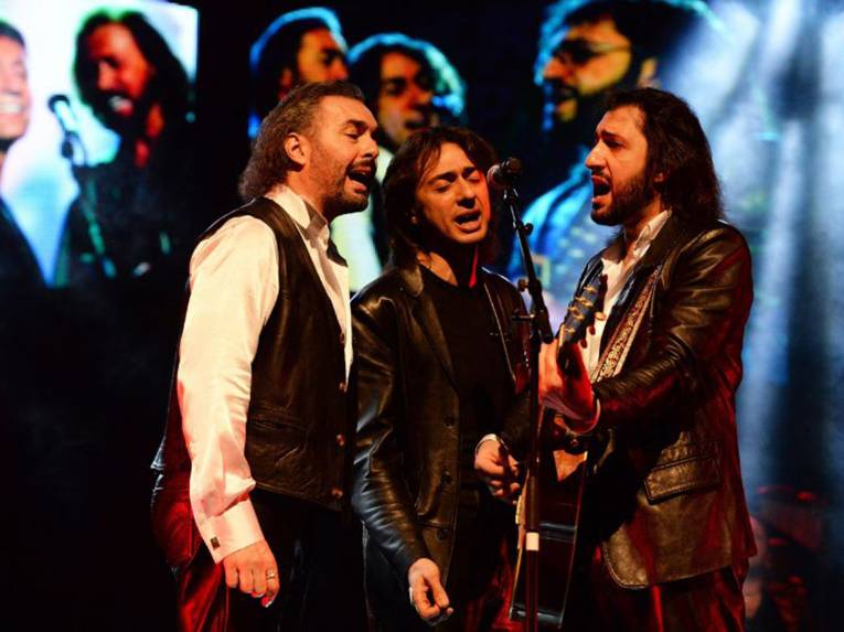 Drei Männer singen auf einer Bühne