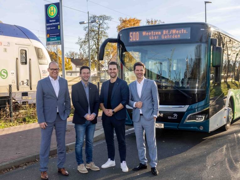 Vier Männer vor einem Bus der Linie 500 am Bahnhof Weetzen.
