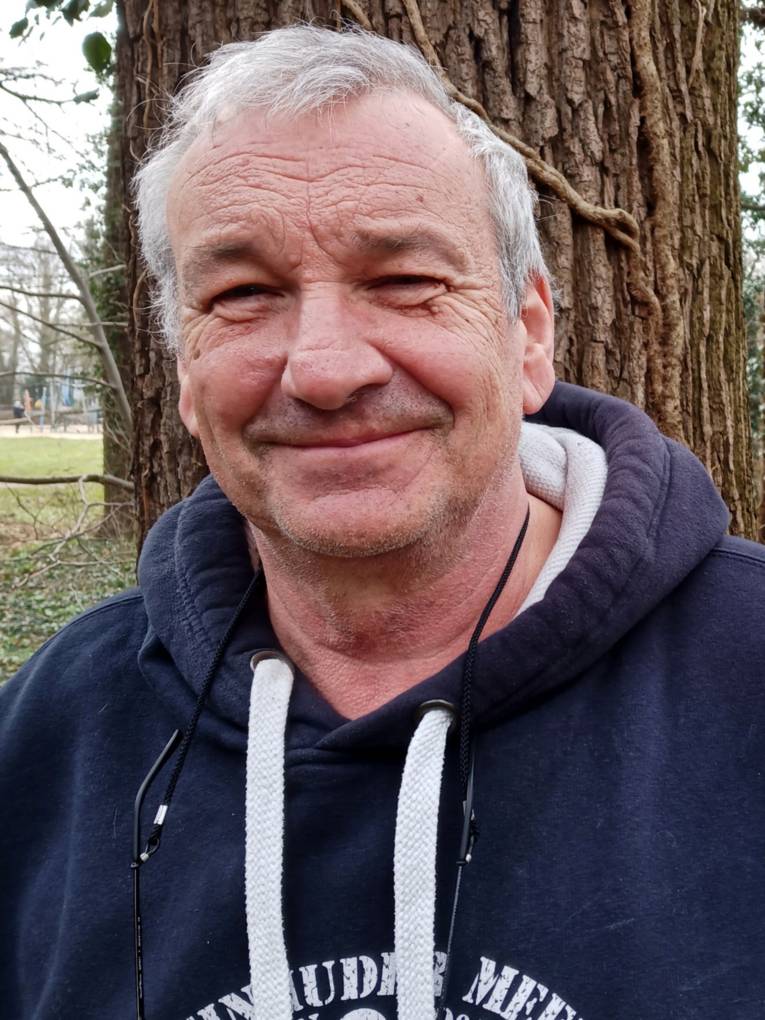 Portraitfoto eines Mannes vor einem Baum.