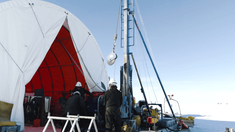 Wissenschaftler mit Sedimentbohrer in Eislandschaft.