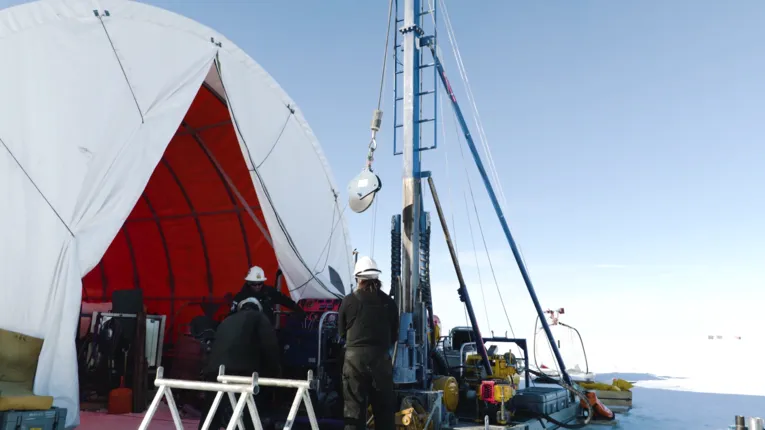 Wissenschaftler mit Sedimentbohrer in Eislandschaft.