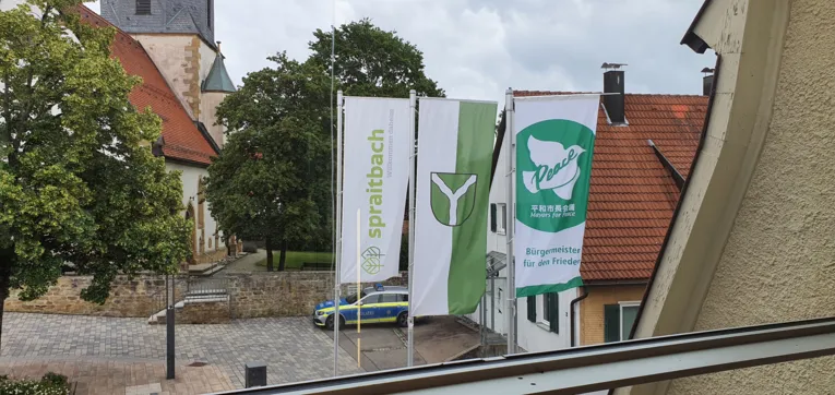 Die Friedensflagge der Mayors for Peace erg&auml;nzt das Gemeindewappen und Logo von Spraitbach