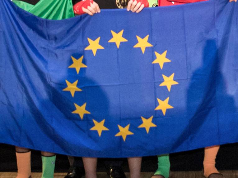 Kinder halten bei einer Sportveranstaltung die Flagge der EU.