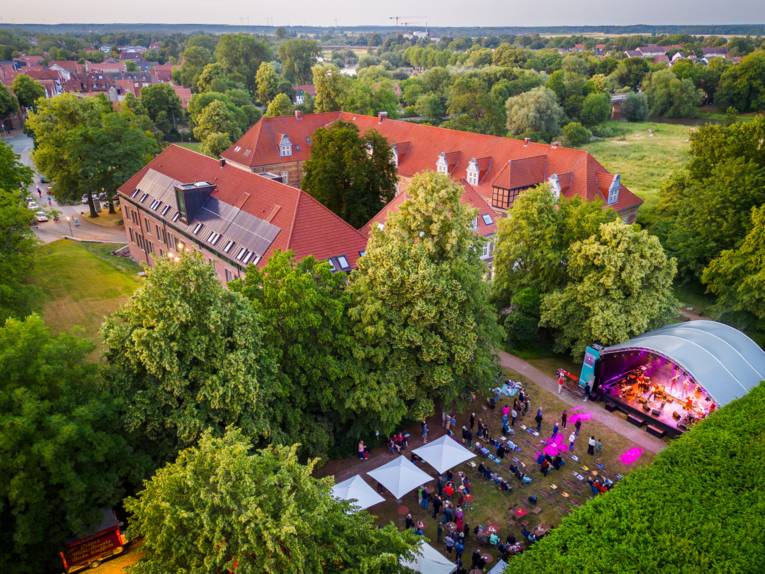 Blick aus der Luft auf den Amtsgarten von Schloss Landestrost in Neustadt am Rübenberge. Publikum verfolgt das Programm auf einer Bühne.