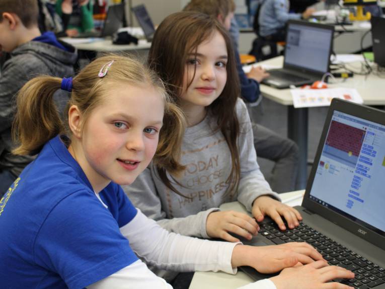 Zwei Mädchen sitzen an einem Laptop