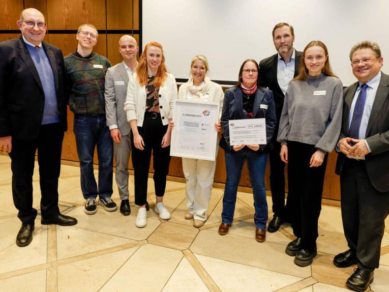 Eine Menschengruppe mit Urkunde auf einer Bühne.