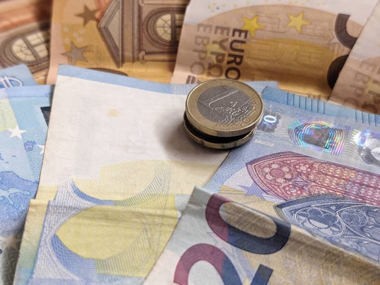 Mehrere Euromünzen liegen auf Euro-Geldscheinen