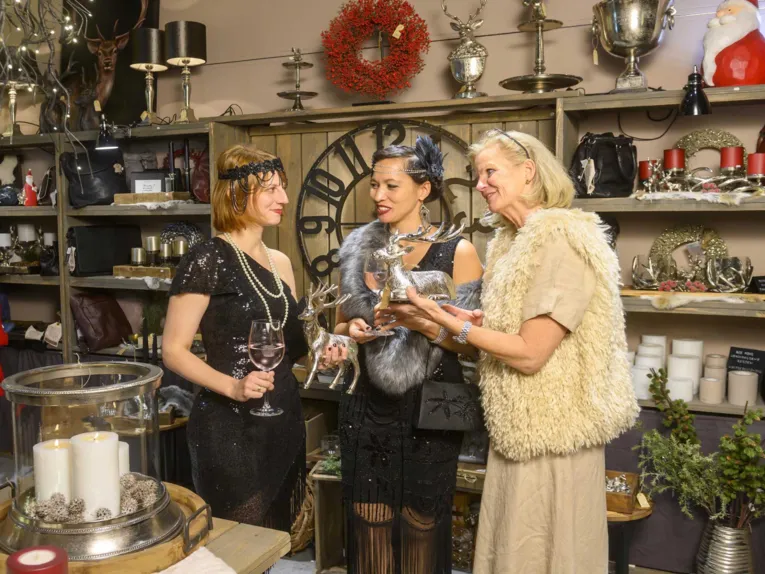 Drei Frauen in Vintage-Kleidung vor einem Verkaufsregal