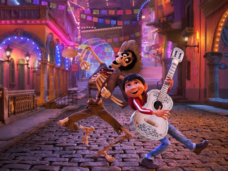 Animation: ein Skelett in Cowboy-Kleidung und ein Kind tanzen auf einer Straße. Das Kind spielt Gitarre