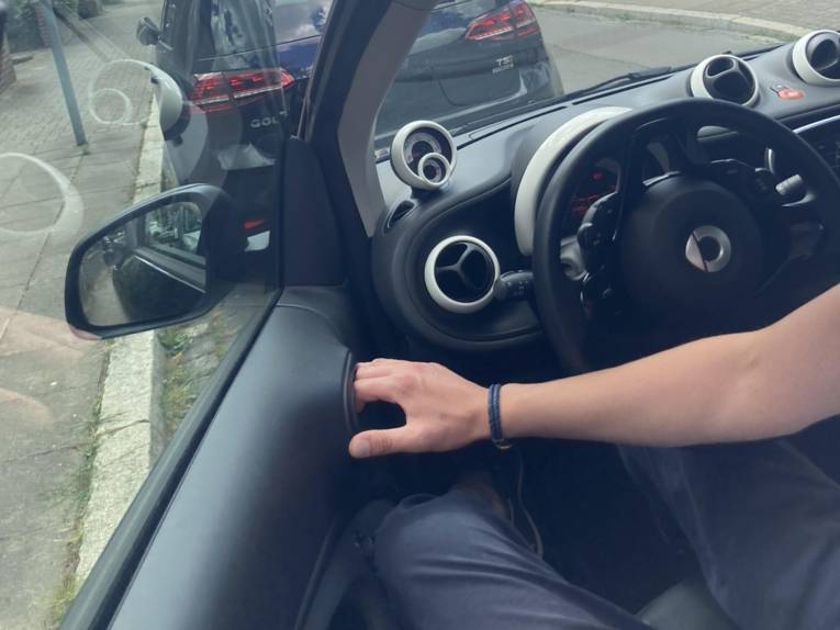 Mann öffnet Fahrertür eines Autos mit der rechten Hand.