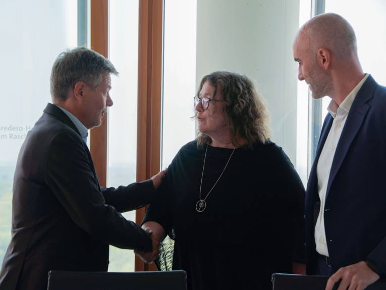 Drei Personen, die sich begrüßen.