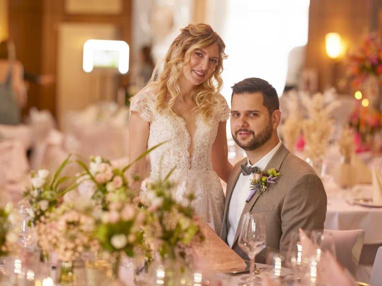 Brautpaar vor festlich gedecktem Tisch.