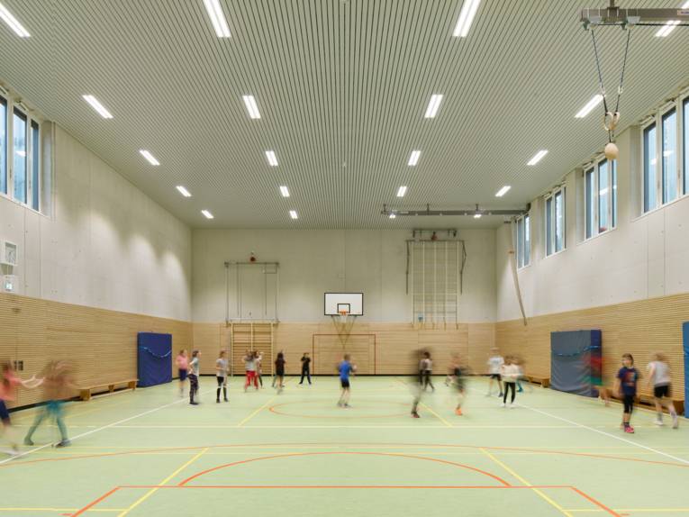 Eine gro&szlig;e Sporthalle mit verwischt fotografierten Kindern beim Sport.