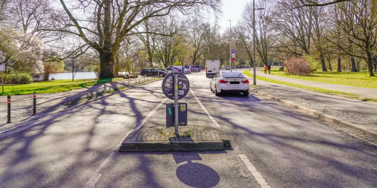 Eine befahrene Straße. Drumherum Grün.