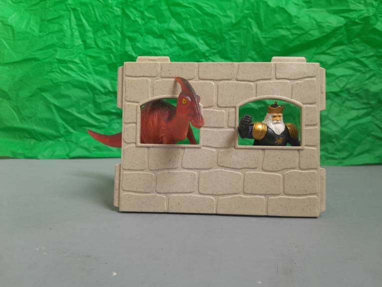 Ein  Spielzeug Dino und ein König schauen durch zwei Fenster in einer Wand.
