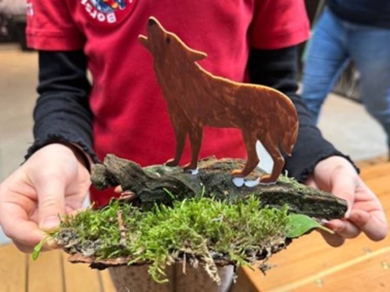 Eine Person h&auml;lt einen gebastelten Wolf vor der Brust.