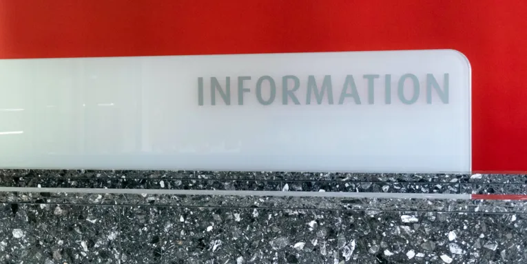 Wort Information vor rotem Hintergrund auf einem steinernen Tresen.
