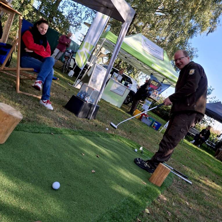 Ein Mann tr&auml;gt Outdoor-Kleidung und spielt Minigolf.