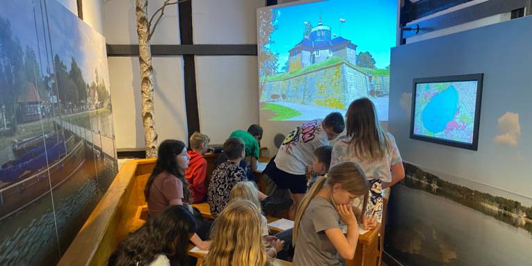 Kinder nehmen an einer virtuellen Bootsfahrt teil.