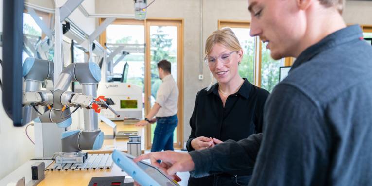 Eine Frau und ein Mann mit Industrieroboter in einem Labor.
