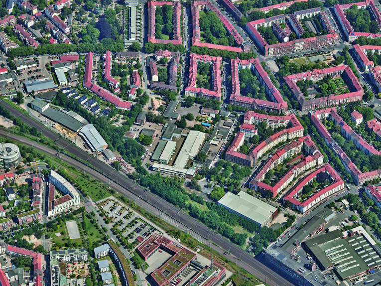 Luftbild eines Quartiers mit Wohnhäusern, weiteren Gebäuden und einer Bahntrasse