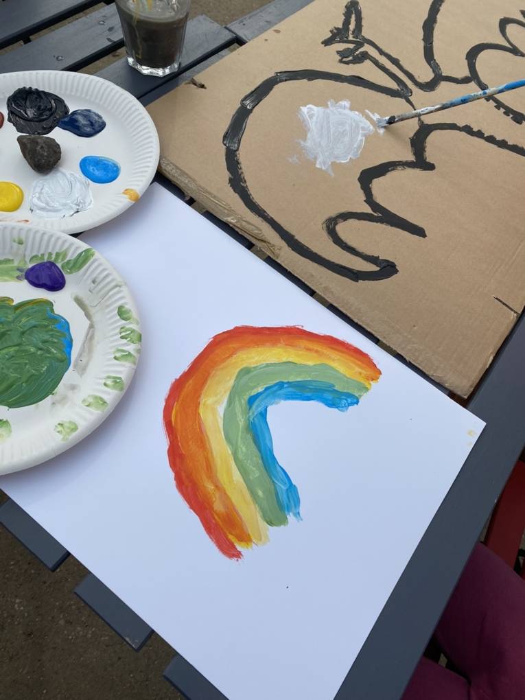 Ein Drache und ein Regenbogen werden auf Pappe gemalt.
