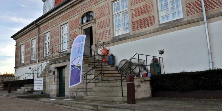 Blick auf Schloss Landestrost, davor steht eine Strandflagge des Naturparks Steinhuder Meer.