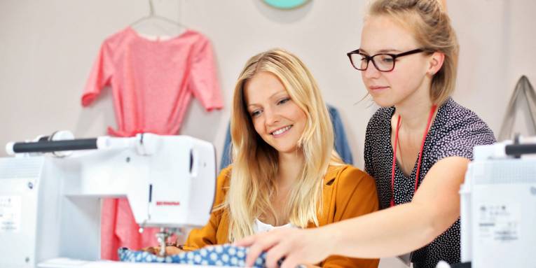 Zwei Frauen an einer Nähmaschine.