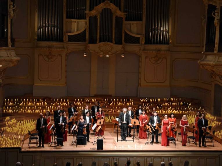 Orchester auf Bühne mit brennenden Kerzen