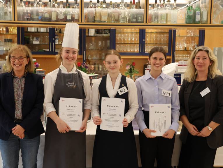 Fünf Personen, drei davon halten eine Urkunde in der Hand