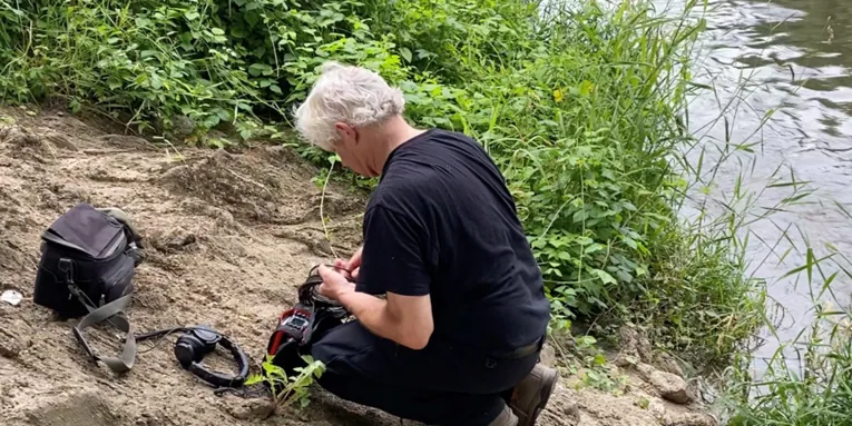Ein Mann mit Ton-Aufnahmegeräten an einem Gewässer