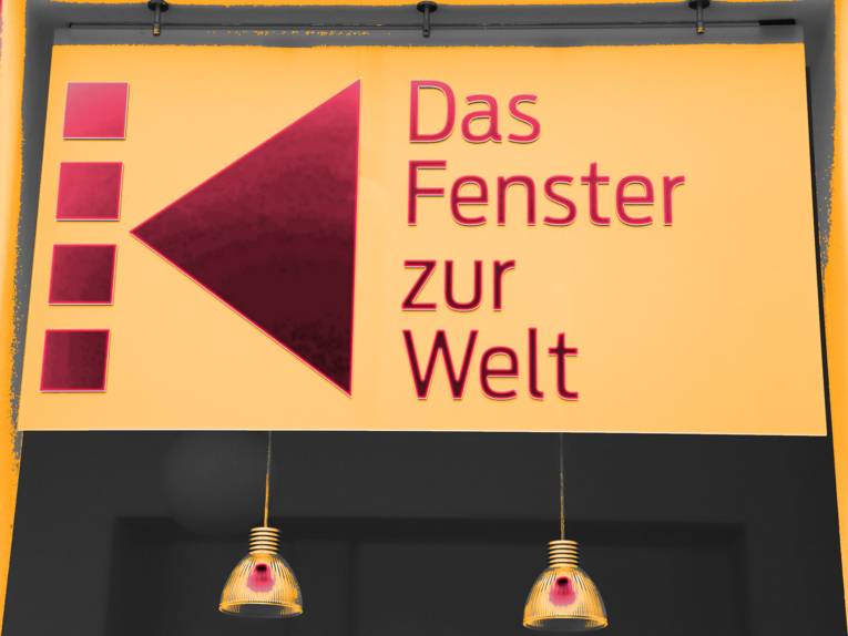 Ein Schild mit der Aufschrift "Das Fenster zur Welt". Der Hintergrund ist gelb, die Schrift rot