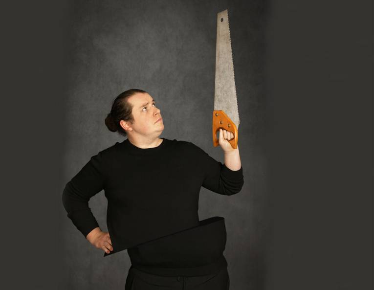 Mann mit Dutt hält eine Fuchsschwanzsäge in die Höhe.