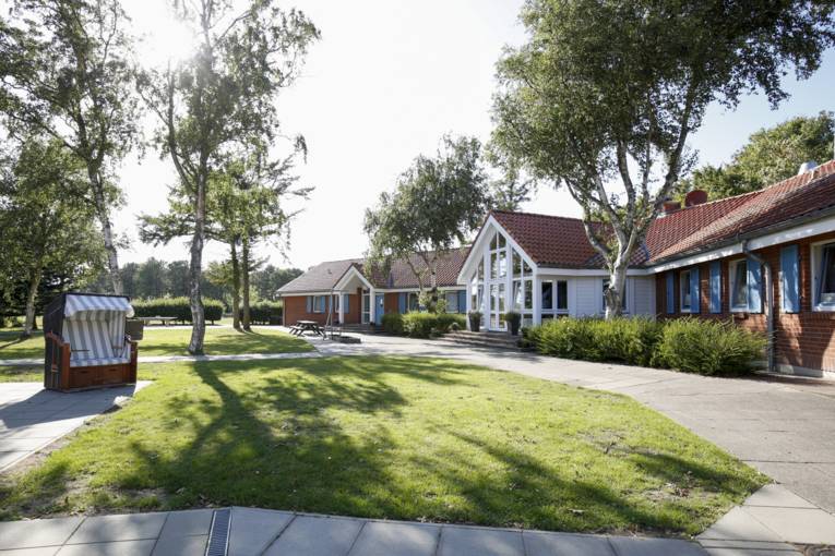 Blick aufs Schullandheim und auf Grünfläche davor. Ein Strandkorb steht ist zu sehen.