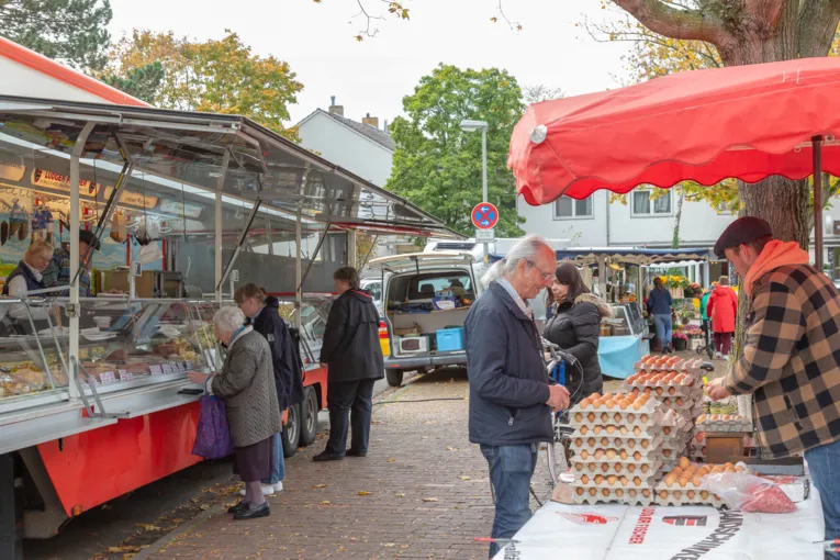 Blick zwischen die Marktst&auml;nde: Kundschaft und Verkaufspersonal auf dem Wochenmarkt