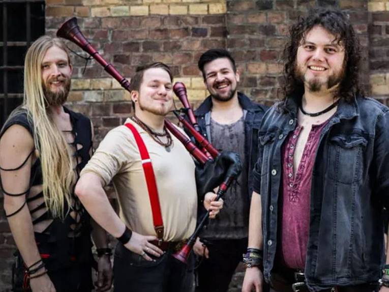 Vier Mitglieder der Band, einer hält einen Dudelsack.